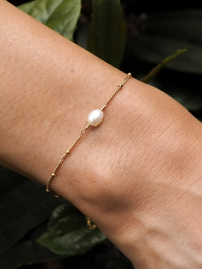 Close-up of a model wearing a freshwater pearl gold satellite chain bracelet.