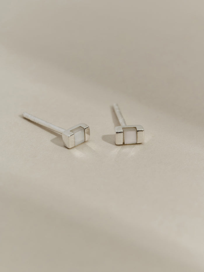 Pair of rectangular silver stud earrings with mother of pearl inlays, displayed on a neutral background.