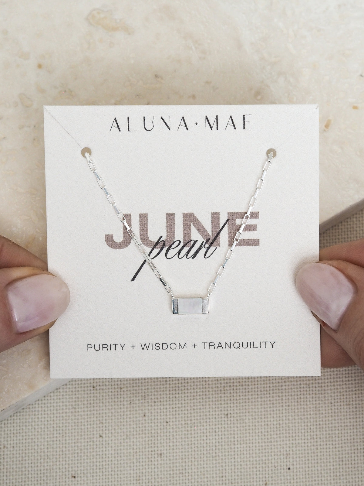 June birthstone necklace featuring a rectangular mother of pearl pendant on a sterling silver box chain, displayed on an Aluna Mae card with birthstone meaning.