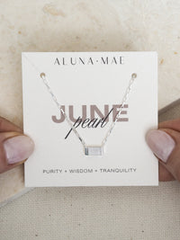 June birthstone necklace featuring a rectangular mother of pearl pendant on a sterling silver box chain, displayed on an Aluna Mae card with birthstone meaning.