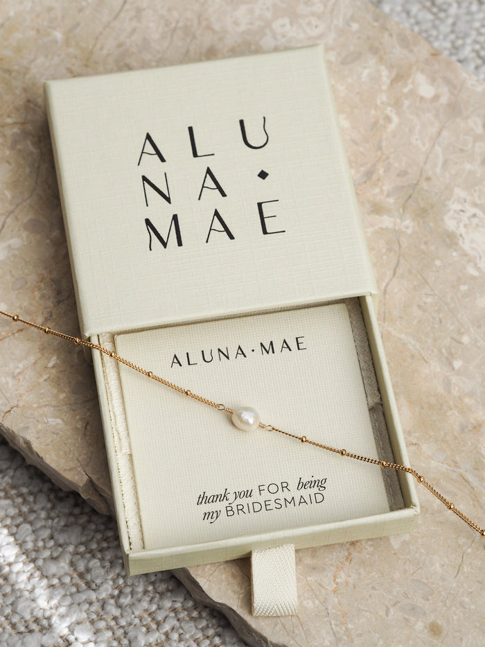 Gold chain bracelet with a single freshwater pearl presented in an Aluna Mae gift box with a "thank you for being my bridesmaid" card.