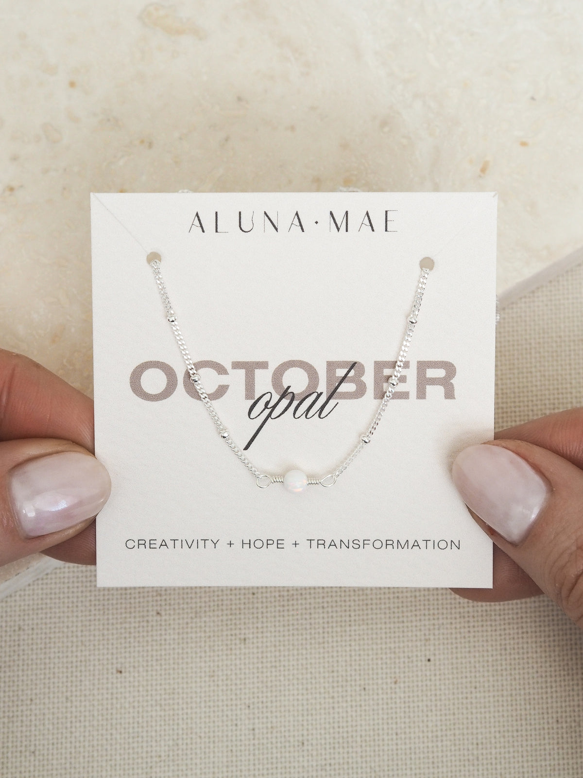 October opal birthstone necklace with sterling silver satellite chain on Aluna Mae card featuring birthstone meaning
