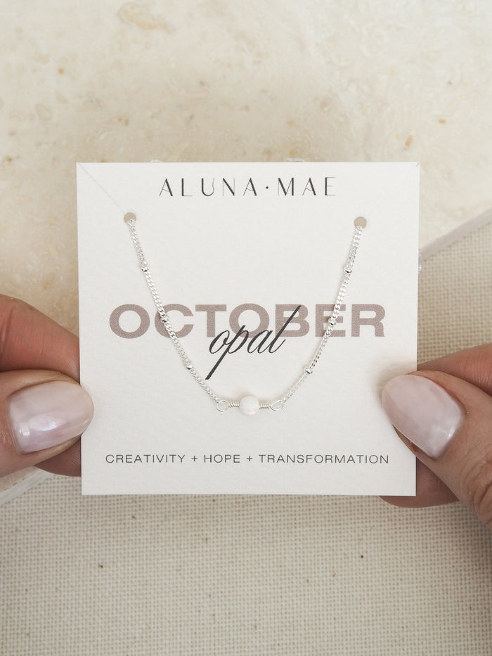 October opal birthstone necklace with sterling silver satellite chain on Aluna Mae card featuring birthstone meaning