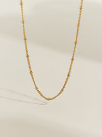 Close-up of a gold-plated satellite chain necklace, featuring evenly spaced tiny gold beads on a delicate chain.