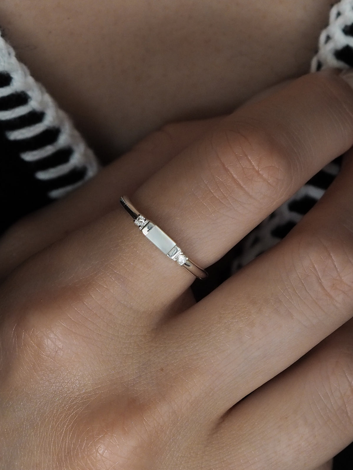 Sterling silver ring worn on a hand, featuring a rectangular mother of pearl centre stone set between two cubic zirconia stones.