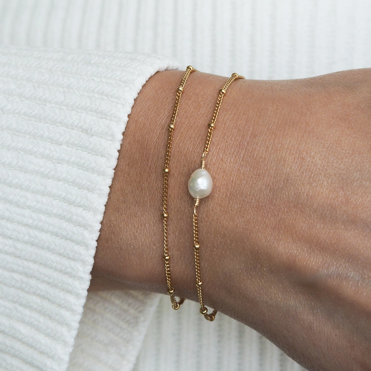 Layered gold-plated sterling silver bracelets with freshwater pearl, minimalist jewelry design for everyday wear.