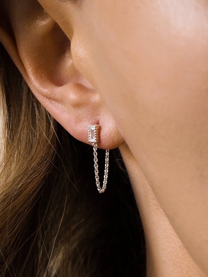 A model wearing sterling silver stud earrings with chain and cubic zirconia gemstones