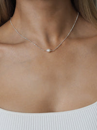 Freshwater pearl necklace with a sterling silver satellite chain, worn by a model in a white ribbed top.
