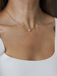 Close-up of a model wearing a freshwater pearl gold satellite chain necklace.