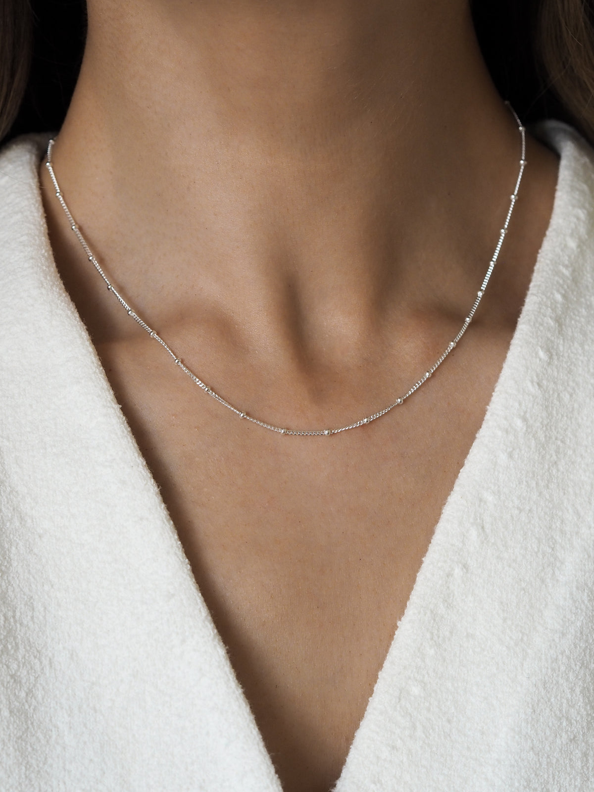 Close-up of a model wearing a sterling silver satellite chain necklace for a minimal look.