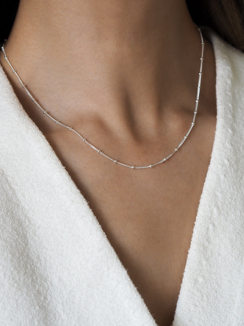 Close-up of a model wearing a sterling silver satellite chain necklace, creating a sleek and minimalistic look.