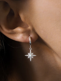 Close-up of a model wearing sterling silver star pendant hoops with opal and cubic zirconia gemstones.