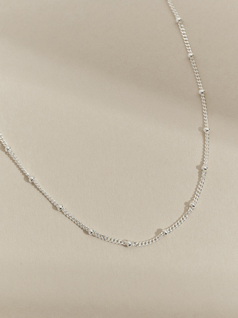 Close-up of a sterling silver satellite chain necklace, highlighting its elegant links and shiny finish.