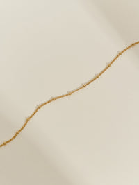 Close-up of a gold satellite chain necklace, capturing its elegant design and polished finish.