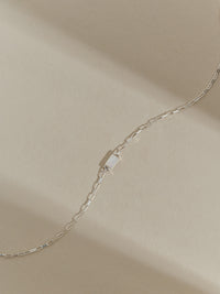 Close-up of a sterling silver box chain bracelet with a mother of pearl gemstone.