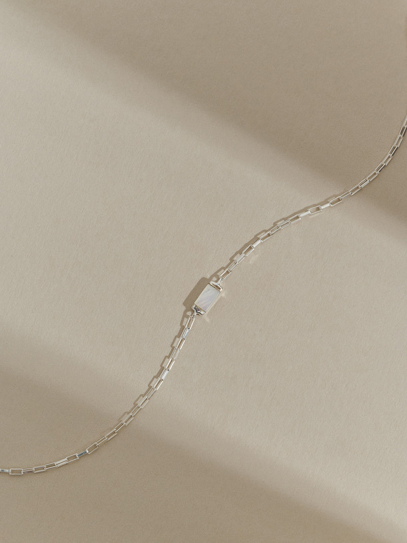 Close-up of a sterling silver box chain bracelet with a mother of pearl gemstone.