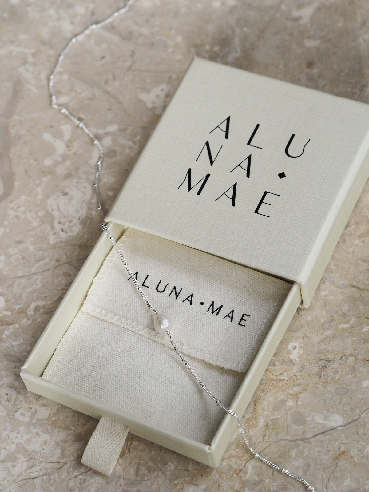 Freshwater pearl necklace with a sterling silver satellite chain, displayed in an Aluna Mae gift box on a neutral marble surface.