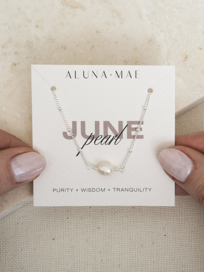 June birthstone necklace featuring a freshwater pearl on a sterling silver satellite chain, presented on an Aluna Mae card with birthstone meanings.