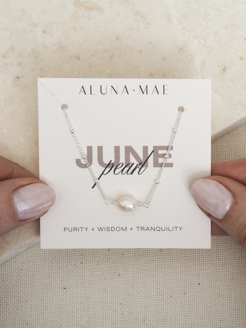 June birthstone necklace featuring a freshwater pearl on a sterling silver satellite chain, presented on an Aluna Mae card with birthstone meanings.