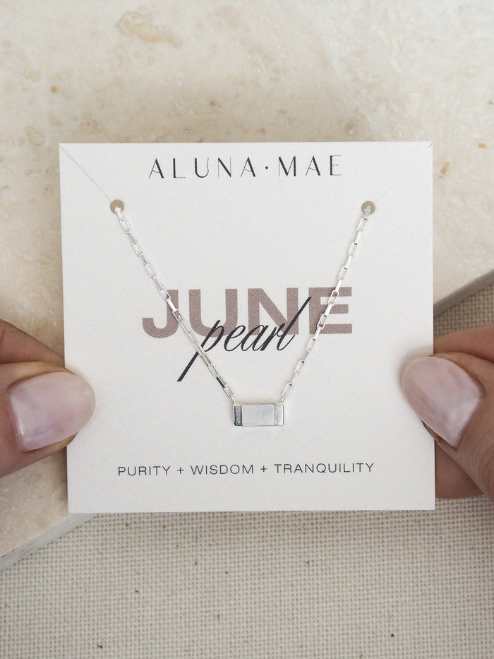 June birthstone necklace featuring a rectangular mother of pearl pendant on a sterling silver box chain, displayed on an Aluna Mae card with birthstone meaning.