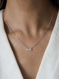 Model wearing a sterling silver necklace featuring a rectangular mother of pearl pendant on a fine box chain.