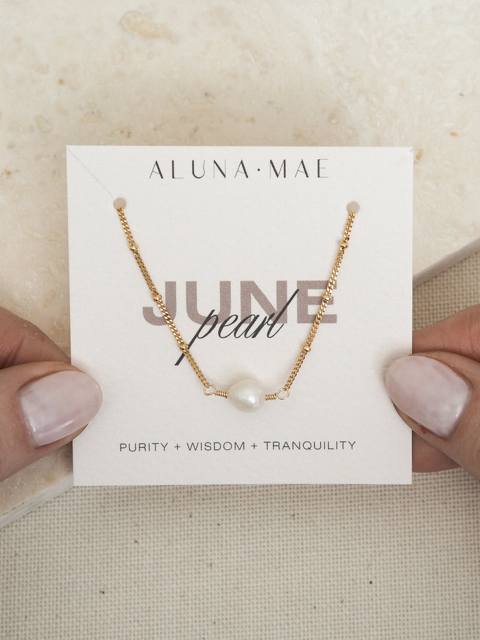 June birthstone necklace featuring a single freshwater pearl on a delicate 18ct gold plated sterling silver satellite chain, displayed on an Aluna Mae birthstone card with the words “Purity + Wisdom + Tranquility.