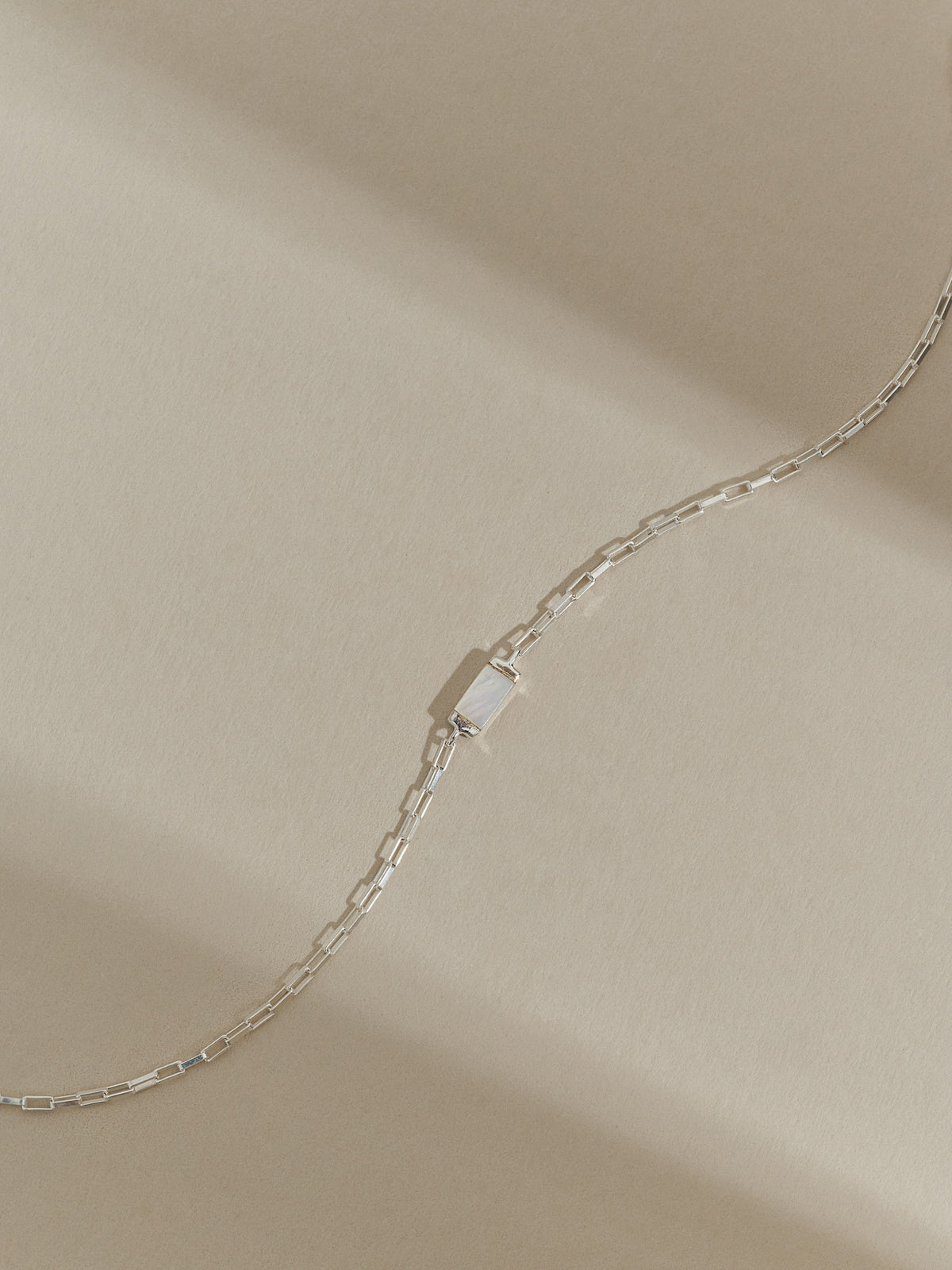 Sterling silver bracelet with a rectangular mother of pearl pendant on a box chain, displayed on a neutral background with soft shadows.