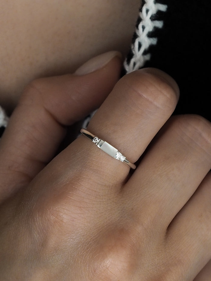Close-up of a hand wearing a sterling silver ring featuring a rectangular mother of pearl stone set between two cubic zirconia stones.