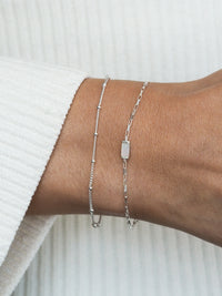 Sterling silver bracelet gift set worn on wrist, featuring a delicate satellite chain and a rectangular mother of pearl pendant on a box chain.