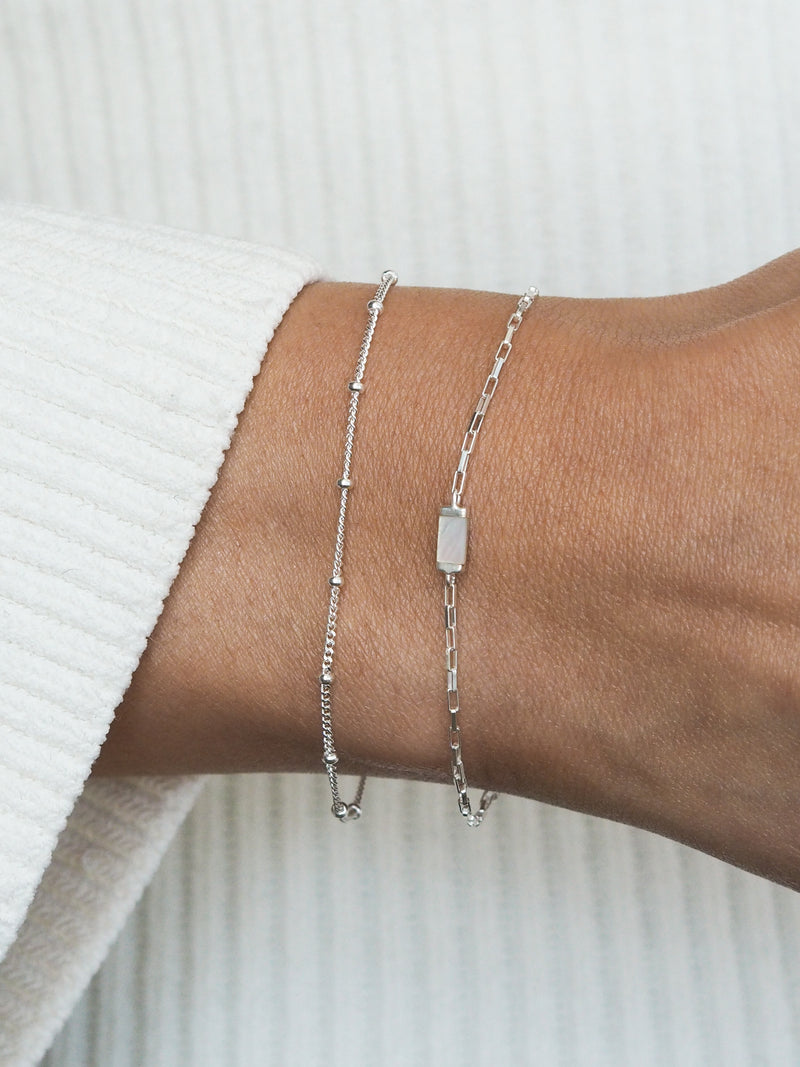 Sterling silver bracelet gift set worn on wrist, featuring a delicate satellite chain and a rectangular mother of pearl pendant on a box chain.