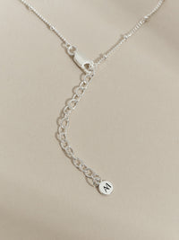 Close-up of sterling silver necklace clasp and extender chain with Aluna Mae engraved tag, shown against a soft neutral background.